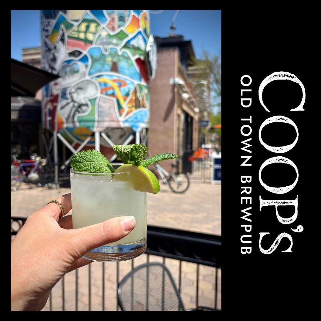 A hand holds a cocktail garnished with lime and mint on a sunny patio, colorful mural and bicycles behind. The text reads “COOP’S OLD TOWN BREWPUB.” Product: 495661530_1273310768136708_386747541244362962_n.