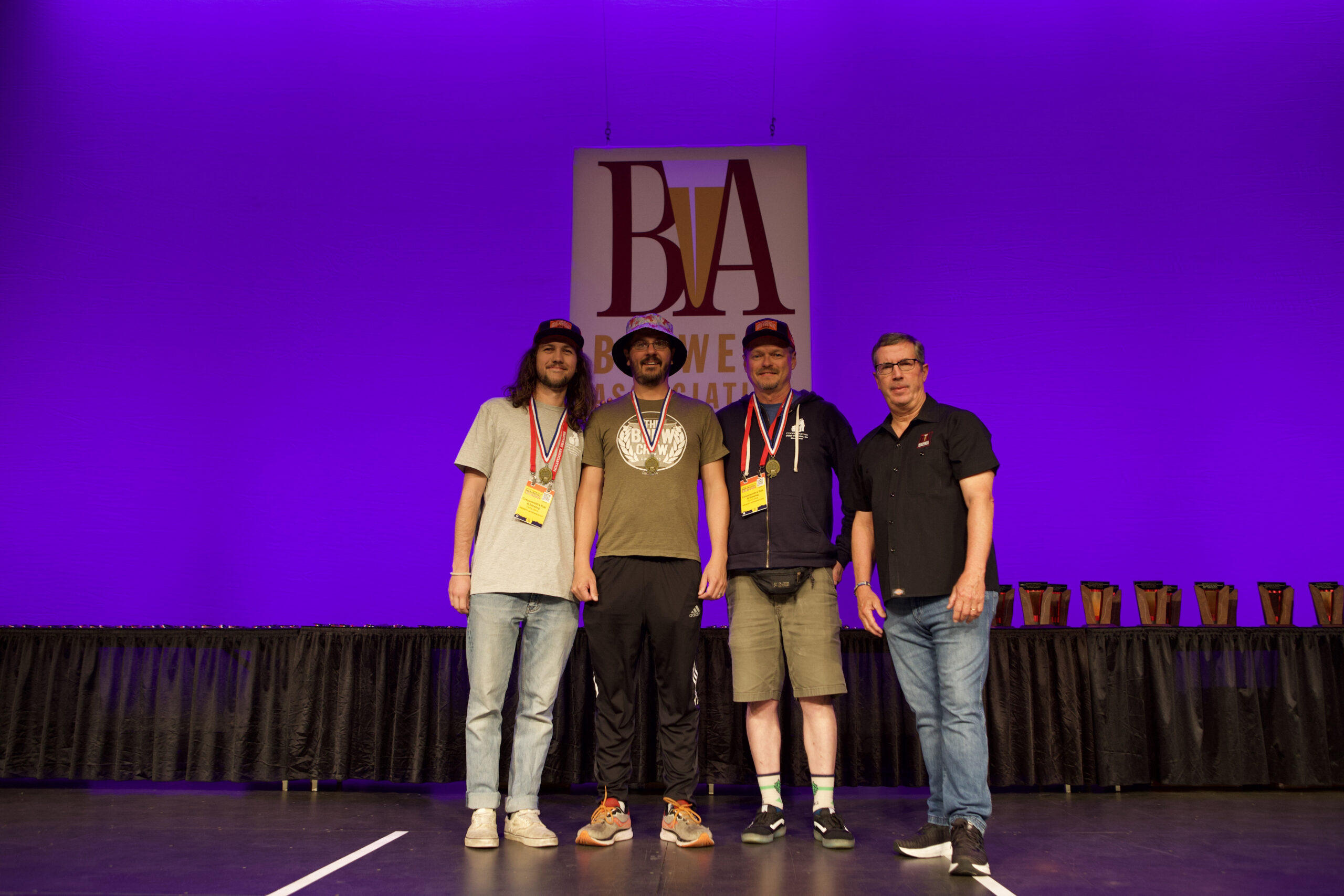 team members from CooperSmith's Pub & Brewing standing on a stage with gold medals around their necks