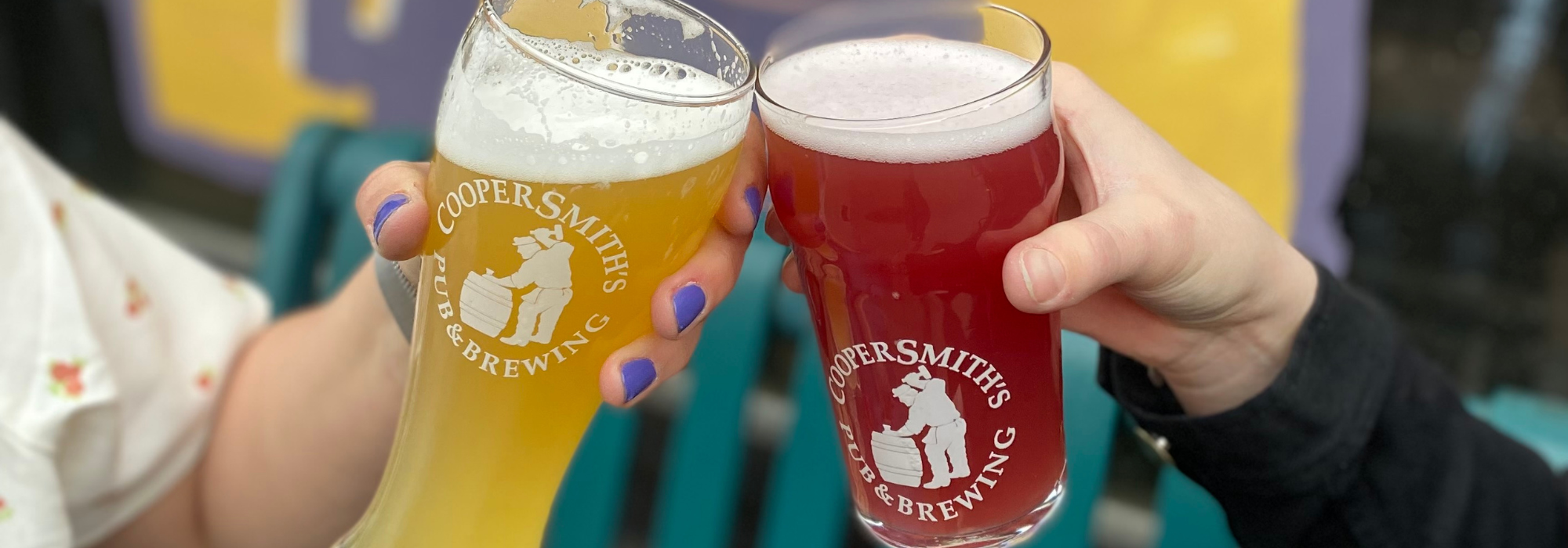 Close up of two people clinking their CooperSmith's glasses together during happy hour